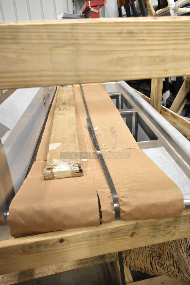 Brand new Regency 600S21620218 stainless steel 2-bay sink with dual drain boards, in crate, packaging intact.