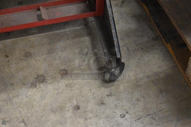 Coats red metal floor-style balancer mate on casters, showing wear. Sturdy construction, ideal for garage use.