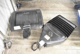 Two brand new scratch and dent light fixtures with mounting hardware on shelf; black finish, minor visible imperfections.