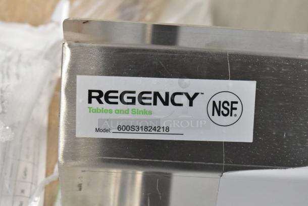 Brand new Regency 600S31824218 stainless steel 3 bay sink with dual drain boards, no legs, scratch and dent condition. NSF certified label visible.
