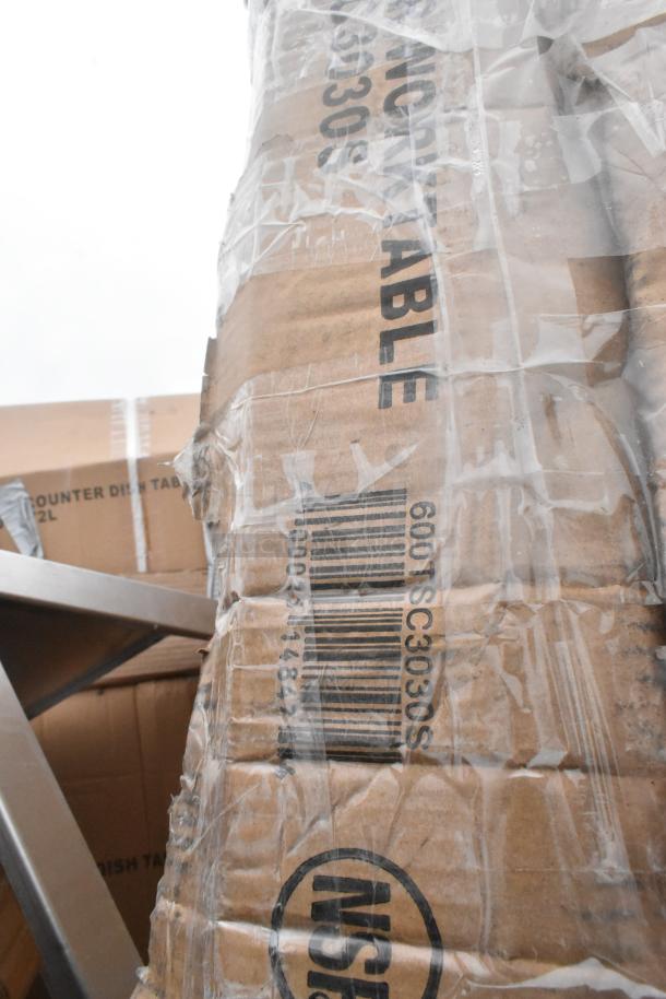 Cardboard packaging showing "60x30 Table" and barcode, indicating a new stainless steel table with some scratches and dents, bundled with other items.