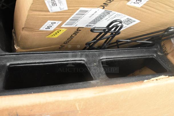 Cardboard boxes labeled "Lancaster, PA" and metal items in black. Items are new, with some dents and scratches.