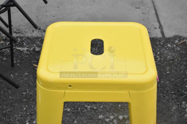 3 yellow metal Tolix style stools, stackable design, bright finish, minimal wear, ideal for both indoor and outdoor use.