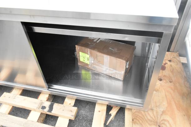 Brand new Regency 600EBTB2496D stainless steel table, 24"x96", 16 gauge, enclosed base with sliding door, midshelf, 6" backsplash.