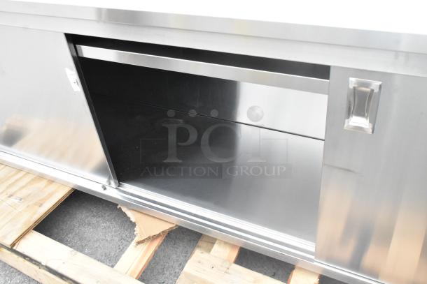 Brand new Regency 600EBTB2496D stainless steel table, 24"x96", with sliding doors, adjustable midshelf, 6" backsplash, minor dents.