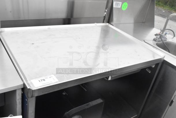 Stainless steel table with drawer, under shelf, and commercial casters. Features durable design, with slight surface marks.
