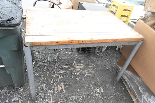 Butcher block wooden table on metal legs, weathered condition, visible screws on top, marked with "175" on the side.