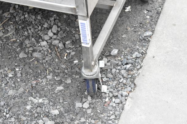 Stainless steel table with under shelf, on commercial casters. Tag with barcode visible, good condition. Ideal for kitchens.