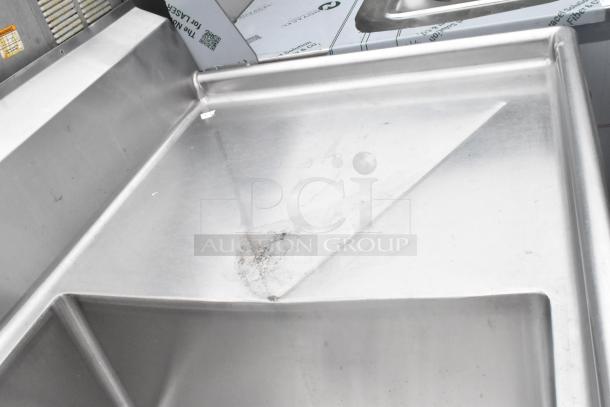 Stainless steel 3 bay sink with dual drain boards, under shelf; minor surface wear visible.