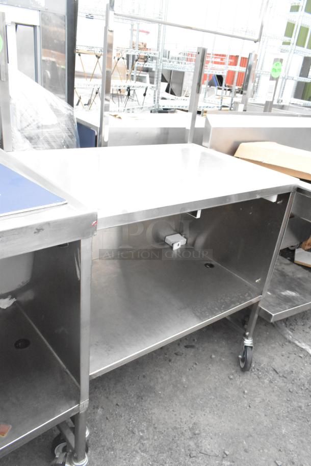 Stainless steel table with under shelf, on commercial casters. Features sturdy build, ideal for commercial use.