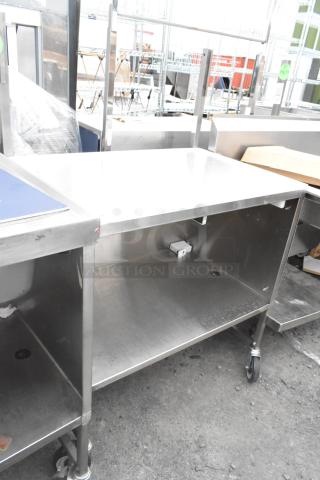 Stainless steel table with under shelf, on commercial casters. Features sturdy build, ideal for commercial use.