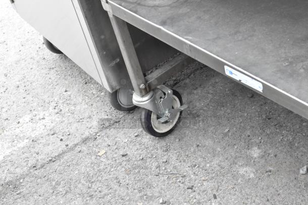 Stainless steel table with under shelf and drawer, equipped with commercial casters, in good condition.