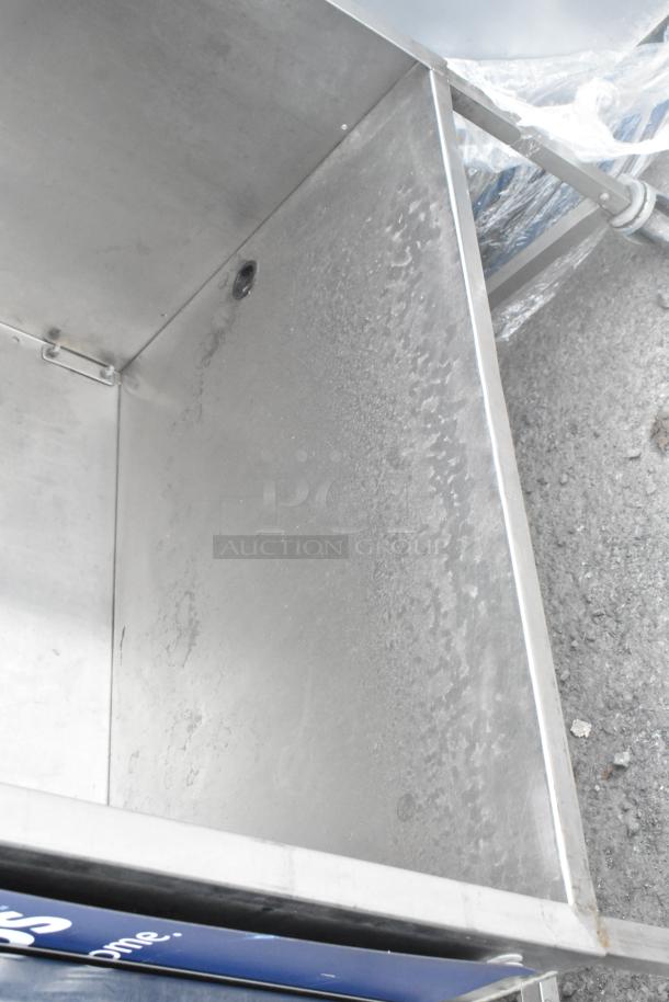 Stainless steel table with under shelf on commercial casters, slightly worn surface, ideal for industrial use.