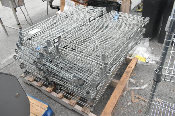 Lot of 30 chrome finish wire shelves on a pallet, stackable, industrial-grade, excellent condition, visible labels and markings.