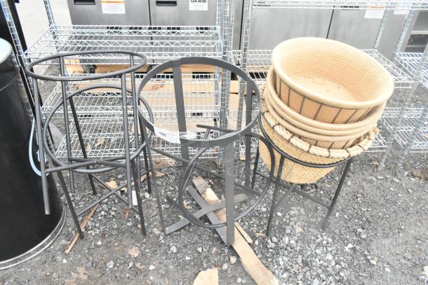 Five various metal stands, black finish, suitable for indoor or outdoor use, stacked baskets included, good condition.