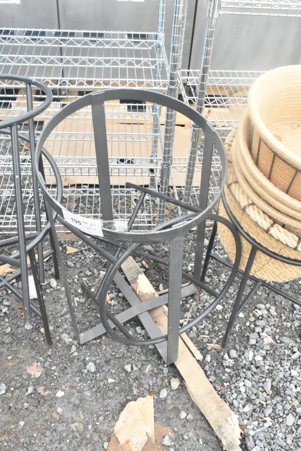 Five metal stands in varying designs, featuring sturdy circular bases. Condition appears good; suitable for various uses.