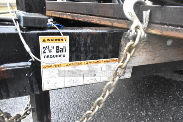 Trailer hitch with safety chains and warning labels indicating a 2-5/16" ball required. Visible wear and rust spots.