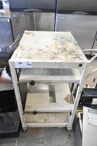 Metal 4 tier cart with commercial casters, showing wear and surface stains, includes labeling indicating auction details.