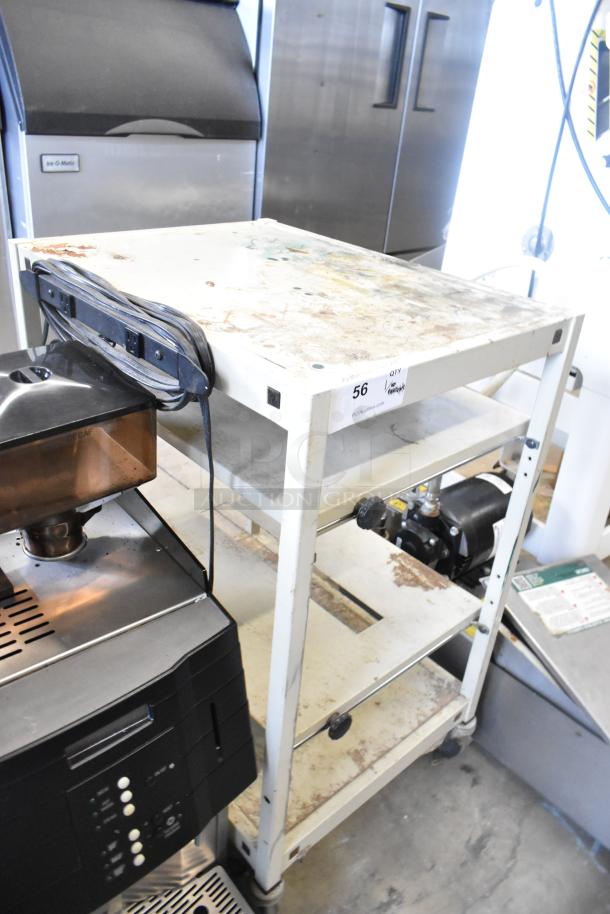 Metal 4 tier cart on commercial casters, sturdy construction, signs of wear and stains visible, equipped with power strip.