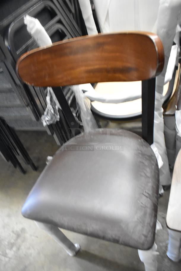 Lancaster Table & Seating black ladder chair with wooden backrest, metal frame, and cushioned seat. New, with minor scratches.