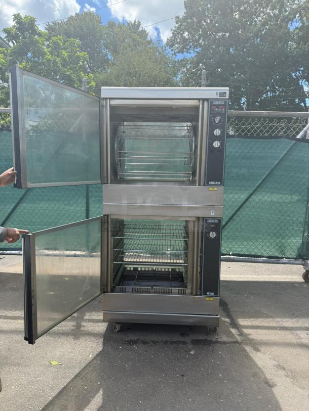 HOBART HRW 303 electric rotisserie oven and warmer with dual compartments, open doors, stainless steel finish, on casters.