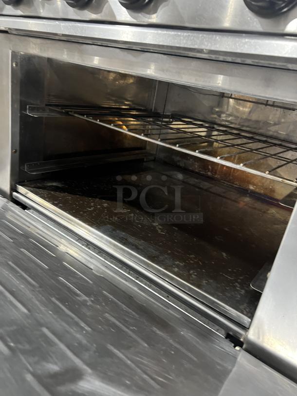 Turbo Air Radiance Series 6-burner range/oven combo, stainless steel, wired rack, natural gas, on casters, with backsplash.