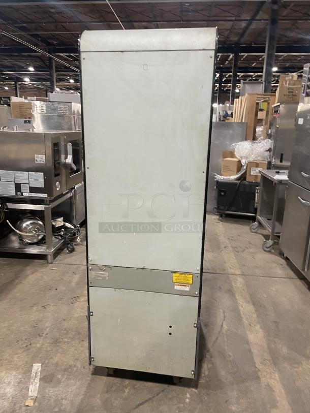 Fri-Jado model CLD25 commercial heated display case, standing in a warehouse. Back panel view, metal shell, 208V, labels visible.