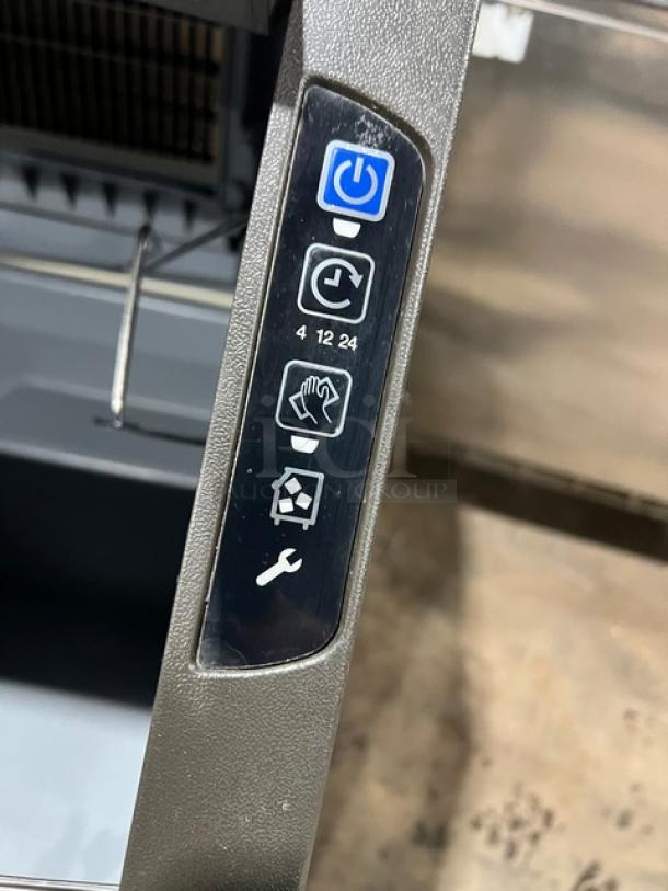 Manitowoc undercounter ice machine control panel with power, timer, and maintenance icons visible.