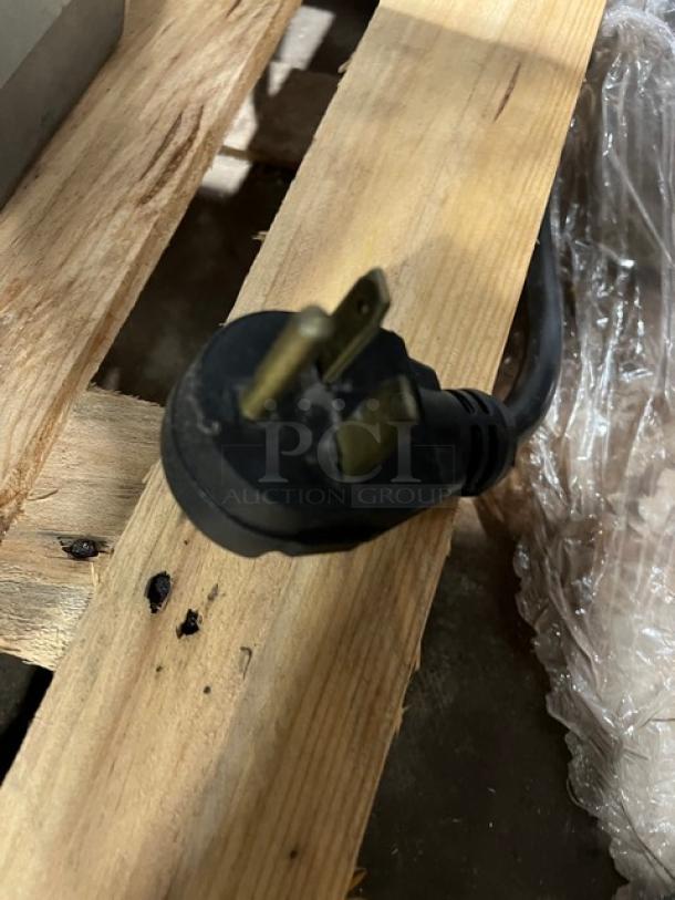 Black electrical plug for Merrychef eikone4 convection oven on wooden surface. Three prongs visible, suitable for 208/240V.