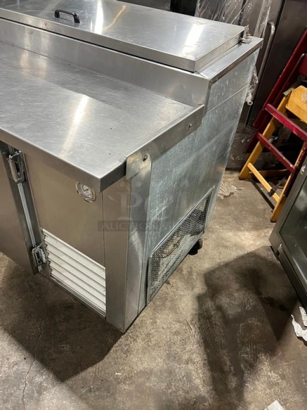 Universal Cooler stainless steel 3-door pizza prep table with poly-coated wired rack, mounted on casters.
