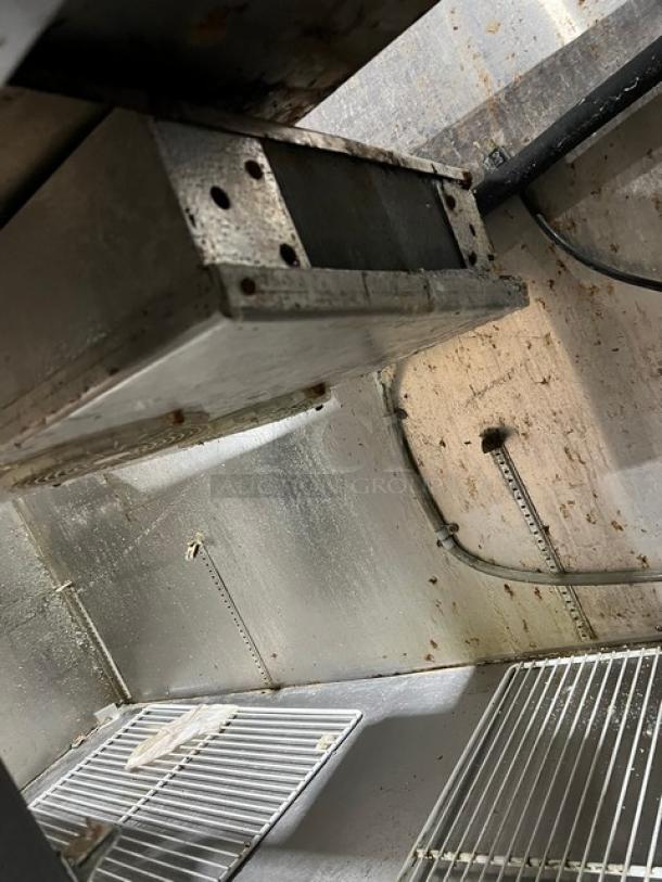 Universal Cooler stainless steel 3-door pizza prep table with poly-coated wired rack and casters, interior view.