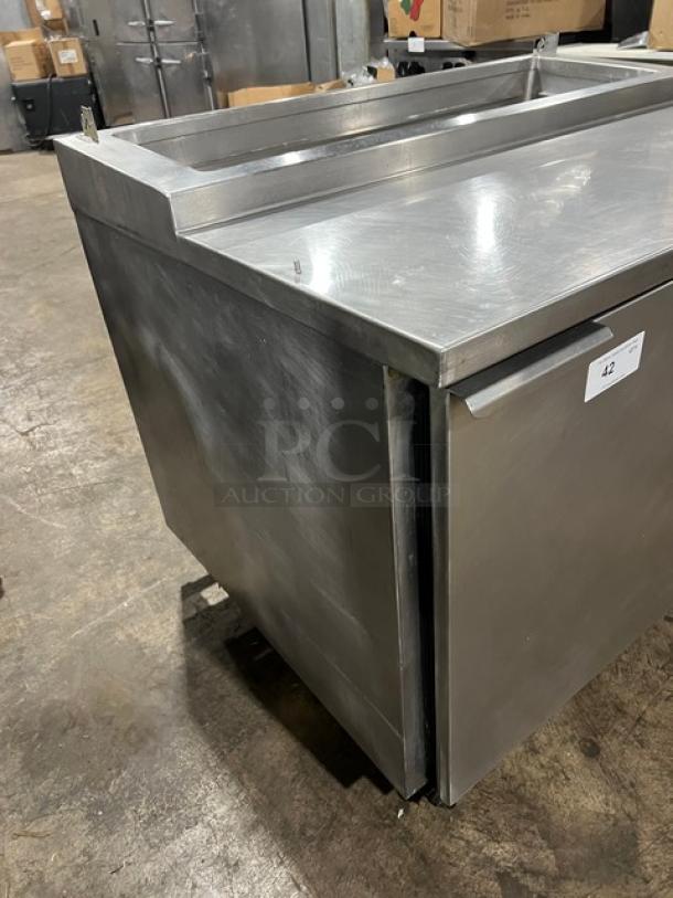 Commercial stainless steel refrigerated pizza prep table with single door, chrome-plated wired rack, on casters.