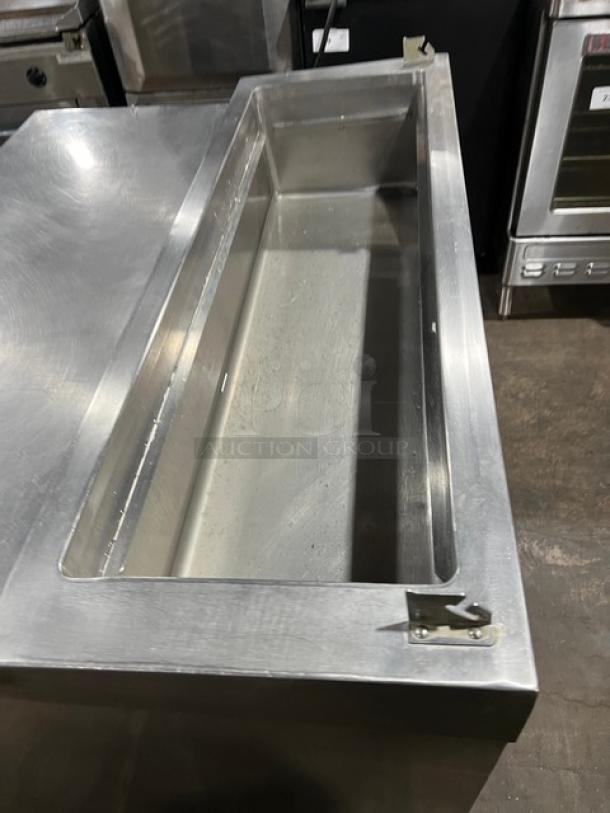 Stainless steel refrigerated pizza prep table with a single door, chrome-plated wired rack, and casters. Appears in good condition.