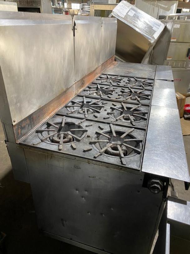 Vulcan commercial stainless steel gas-powered range with 8-burner split-top, flat griddle, triple oven, backsplash, and casters.