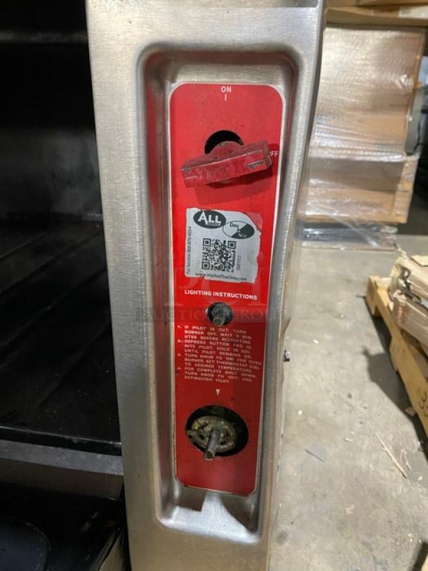 Vulcan stainless steel gas 8-burner range with flat griddle, triple oven, backsplash, and wired rack on casters.