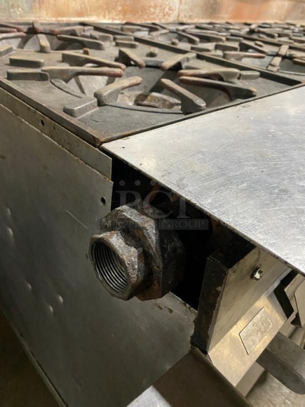 Vulcan commercial stainless steel gas 8-burner range with flat griddle, triple oven combo, back splash, on casters.