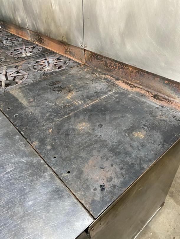 Vulcan stainless steel gas-powered range with 8-burner, split-top griddle, triple oven combo, backsplash, and casters. Signs of wear visible.