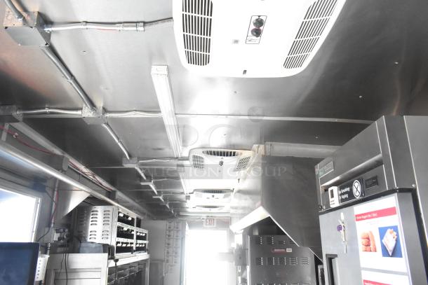 Interior of a 24' mobile kitchen trailer featuring stainless steel appliances, commercial equipment, and ventilation system.