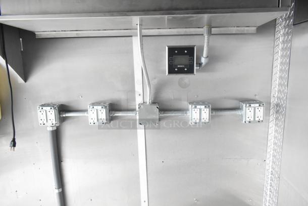 Electrical panel and outlets in a 24' Cruising Kitchens fast food trailer, featuring steel surfaces and wiring setup.