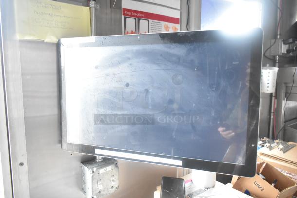 Interior view of a mobile kitchen trailer featuring a mounted screen and control switches. Signs and notes visible nearby.