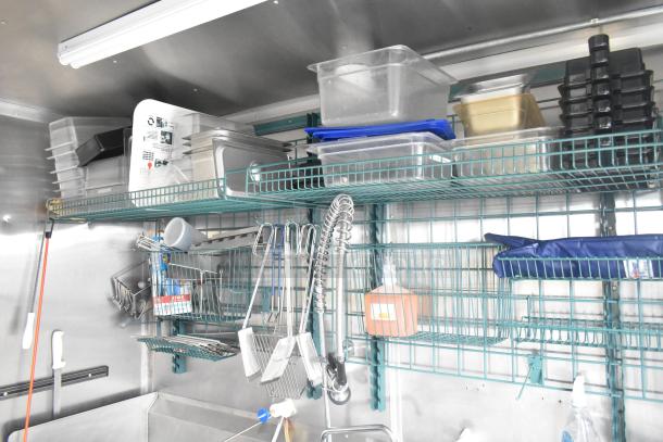 Interior of Cruising Kitchens 24' fast food trailer with shelves holding various kitchen equipment, utensils, and storage containers.
