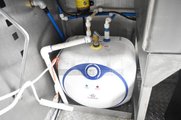 Eccotemp tankless water heater installed in a mobile Burger King kitchen trailer, featuring various pipe connections.