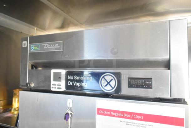True freezer in new condition, featuring a digital display and "No Smoking or Vaping" sign, part of a fully equipped mobile kitchen trailer.