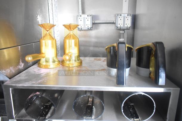 Golden dispensing nozzles and black dispensers on a metal shelf inside the Cruising Kitchens 24' Burger King fast food trailer.