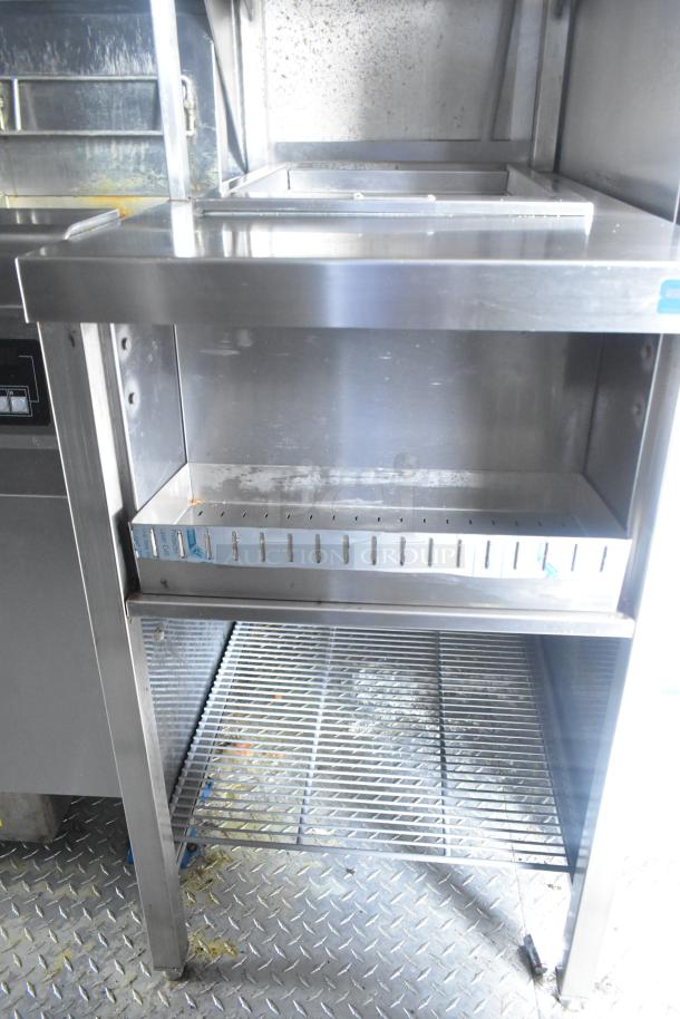 Interior view of a Cruising Kitchens 24' mobile kitchen trailer, featuring stainless steel shelving and equipment space.