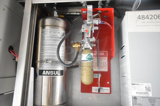 Commercial-grade fire suppression system in a mobile kitchen trailer. Features Ansul equipment with detailed safety labeling.