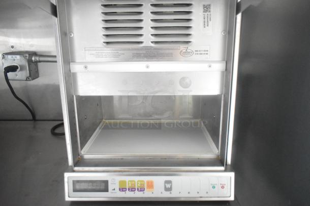 Commercial-grade warming station with digital controls, vented design, and visible ComServ label in mobile kitchen trailer.