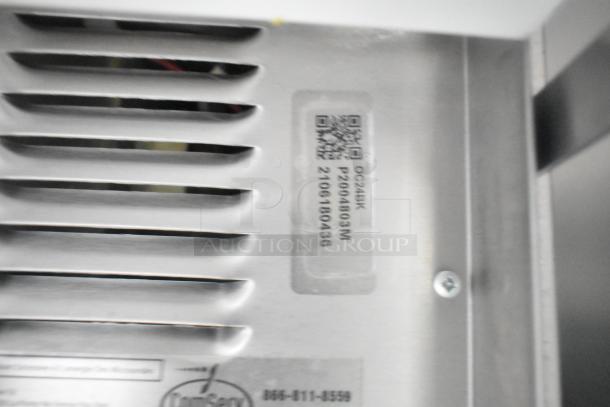 Ventilation grate with a QR code and serial number plaque, marked "QC245K P2004803M 2105180436," on a commercial kitchen appliance.
