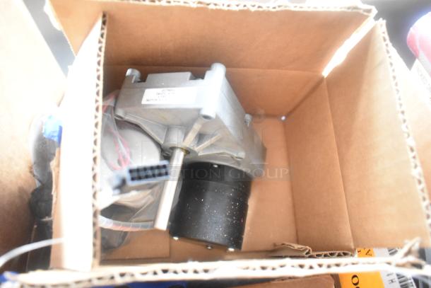 Cardboard box containing electrical motor part with visible wiring and connectors. No visible labels or markings.