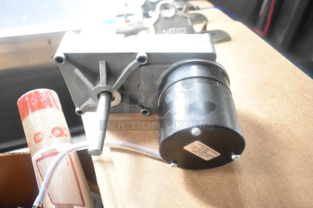 Industrial motor with attached wiring and metal components, resting on a wooden surface.